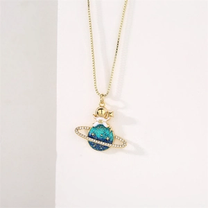 Detail of gold astronaut sitting on blue-green crystal planet pendant with zircon stones