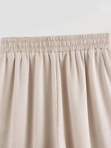 Détail de la taille élastique sur un pantalon plissé beige avec texture verticale