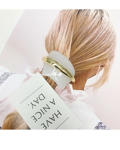 Detail of white resin hair clip with gold metal finish worn on elegant hairstyle