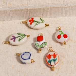 Close-up of ceramic flower and cherry charms with 18K gold plated metal rings