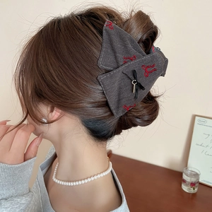 Detail shot of the dark grey fabric bow hair claw clip showing practical head wear effect