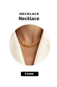 Detail of twisted rope chain necklace in 18K gold plated finish styled with white blazer