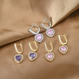 Flat lay of heart-shaped zircon earrings in multiple colors on elegant brown silk fabric