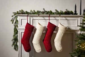 Row of red and cream knitted Christmas stockings hanging on a white wooden mantel