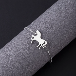 Macro shot of silver unicorn pendant bracelet displayed on a professional textured stand