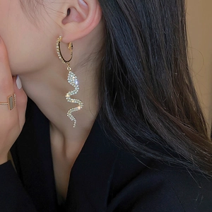 Close-up of elegant gold snake drop earrings with sparkling rhinestones on model