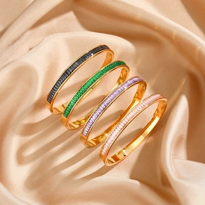 Macro detail of gold-plated stainless steel bangles with colorful baguette-cut zircons