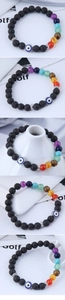 Macro view of volcanic lava stone beads and colorful chakra eye bracelet on magazine