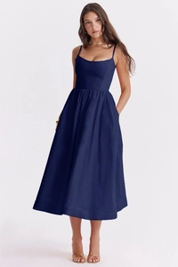 Detail of a deep blue midi dress with thin straps, high-waisted pleats, and side pockets