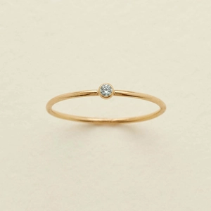 Close-up of minimalist gold ring with December birthstone on textured beige background
