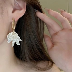 Elegant white acrylic flower drop earrings with gold hooks on a fashion model