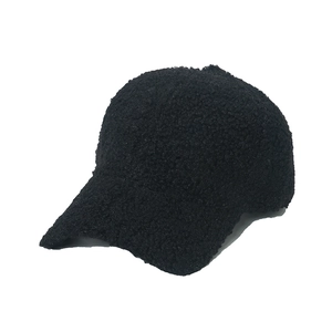 Close-up of fluffy black faux lamb wool fabric texture on a warm winter baseball cap