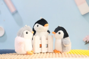 Detailed view of three small plush penguin dolls in black, grey and pink colors