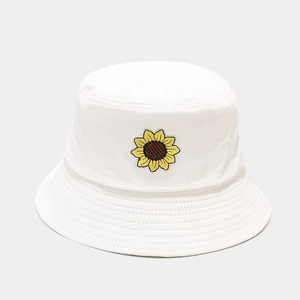 Dettaglio del ricamo a girasole su un cappello a secchiello bianco in cotone