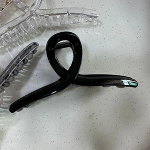 Glossy black and transparent 13cm large hair claw clips for thick hair on white surface