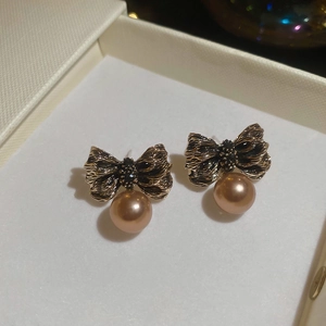 Détail de boucles d'oreilles nœud doré vintage avec pendentif perle de champagne