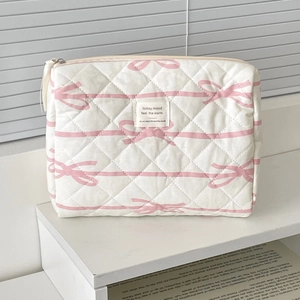 Detailed macro view of quilted makeup bag with pink bow pattern and zipper texture