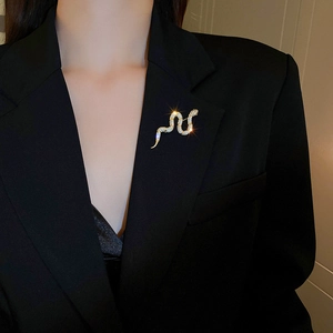 Close-up of gold-plated snake brooch with sparkling crystals on a black suit lapel