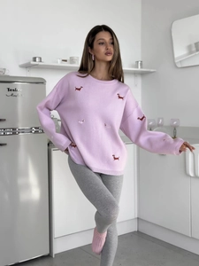 Detail of pink knitted sweater featuring red dachshund embroidery in a lifestyle setting