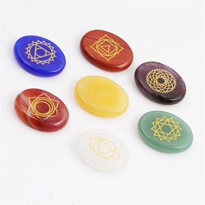 Polished chakra stones set with gold engraved healing symbols on white background
