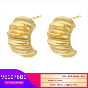 Macro shot of gold-plated brass hoop earrings with elegant vertical textured ridges
