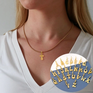 Detail view of a gold beaded necklace featuring a letter T pendant and A-Z options