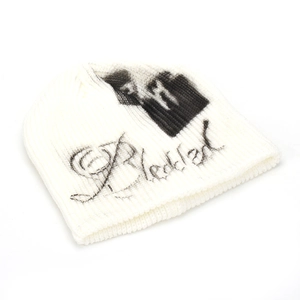Close-up of white ribbed knit beanie featuring black gothic letter and street style print