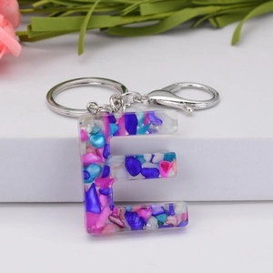 Detailed macro of resin letter E keychain with colorful natural stones and silver clasp