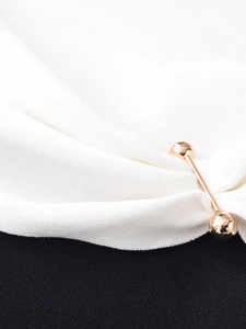 Detailed view of the gold-toned metal shoulder embellishment on a minimalist knitted top