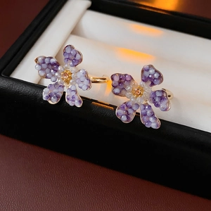 Macro detail of vintage floral earrings with purple and white petals on a jewelry box