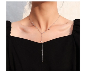 Model wearing a silver Y-shaped tassel necklace with small beads in polished titanium steel