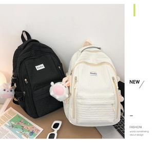 Détail de sacs à dos matelassés noir et beige avec pendentif lapin mignon et accessoires