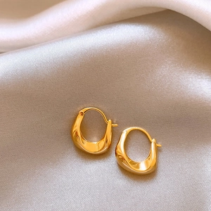 Boucles d'oreilles géométriques dorées en U sur fond élégant en soie argentée
