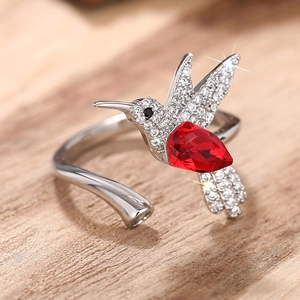 Detailopname van kolibrie ring met rode druppelsteen en glinsterende vleugels