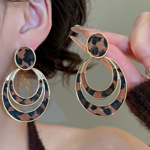 Detail view of double circle leopard print earrings with gold metal frame on a model