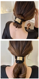 Détail d'un chouchou en tissu noir avec boucle dorée texturée sur une queue de cheval basse