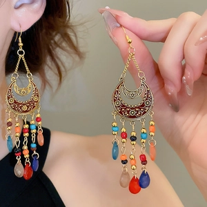 Detail of bohemian gold moon earrings with colorful beads and red enamel accents