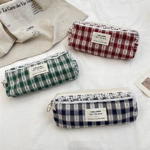 Detailed view of canvas pencil cases with white lace trim and metal circular zipper pulls