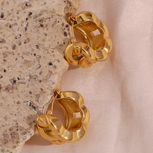 Macro shot of 18K gold plated thick twisted hoop earrings on a natural stone base