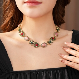 Détail d'un collier vintage doré avec cœur rouge et pendentif en relief rose sur un mannequin