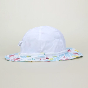 Dettaglio di cappello da sole in cotone bianco con stampe di fenicotteri e ananas