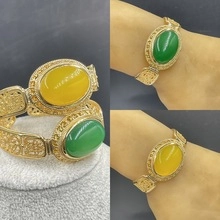 Detail of vintage gold open cuff bracelets with large green and yellow gemstones