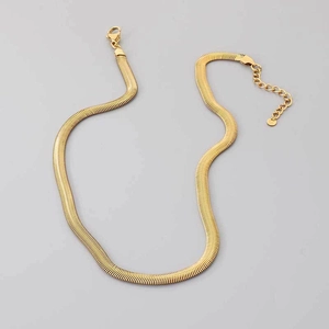 Dettaglio di una collana a catena piatta a serpente dorata con chiusura a moschettone