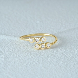 Macro detail of adjustable gold silver ring featuring six sparkling parallel zircons