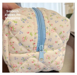 Close-up of smooth blue zipper and diamond quilted floral cotton fabric texture