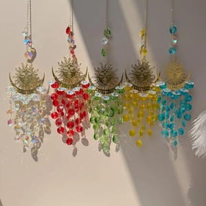 Detail of sun and moon crystal suncatchers casting colorful light reflections on a wall