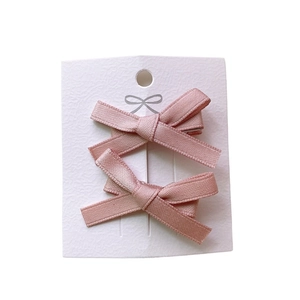 Set of two pink silk ribbon bow hair clips for girls displayed on white card packaging