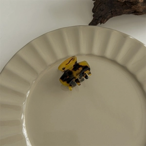 Close-up of a large tortoiseshell acetate shark hair claw clip on a ceramic plate