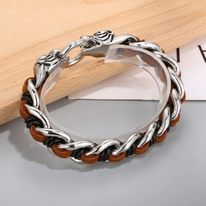 Close-up of titanium tiger head bracelet with braided brown and black leather layers