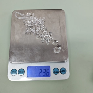 Macro shot showing the 23.6g weight of a clear acrylic snowflake pendant on a digital scale